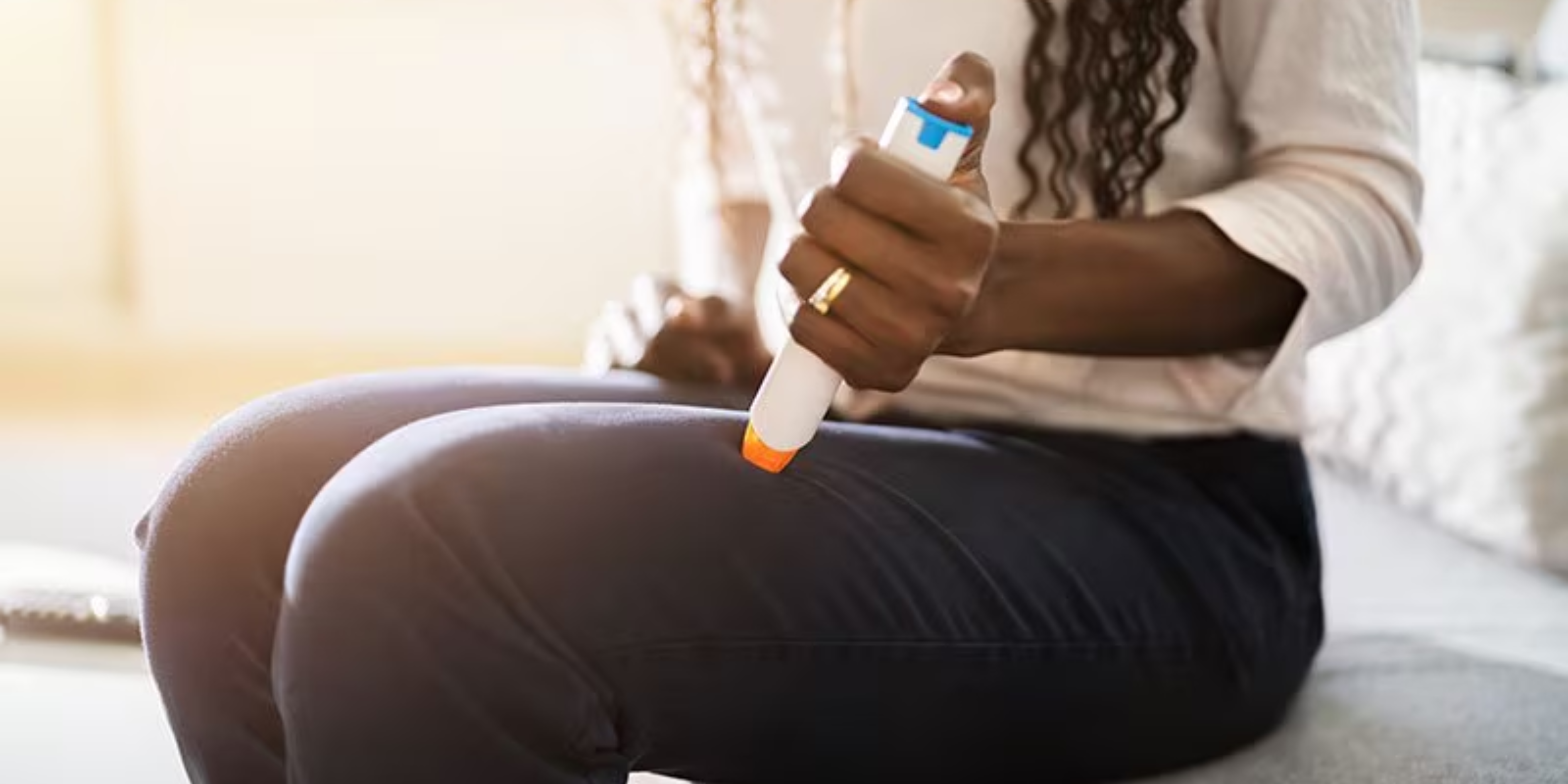 A picture of a woman who is injecting an epipen into her thigh