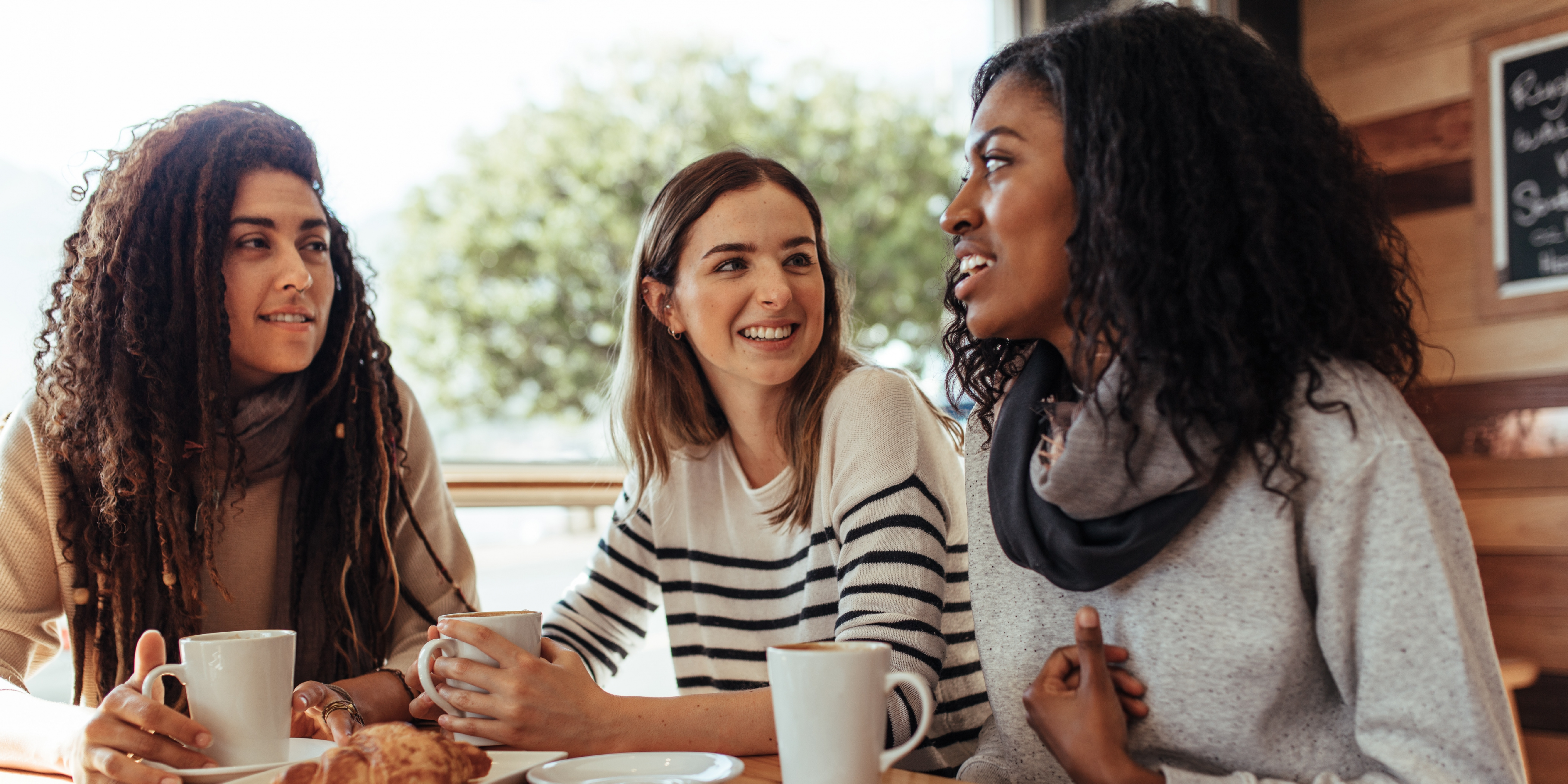 A picture of a group of 3 friends talking in a coffee shop